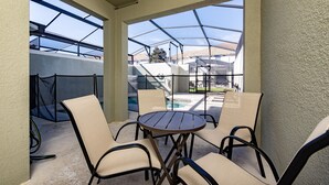 Un espace extérieur aménagé, abrité et doté d’une piscine, de chaises et d’une structure en verre.