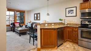 A modern kitchen with granite countertops, stainless steel appliances, and wooden cabinetry. - Ski In Ski Out | Zephyr Mountain Lodge 2219 | Hot Tub | Base Area (Winter Park)
