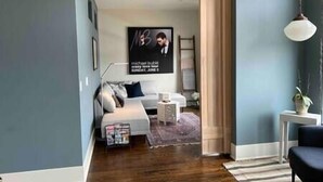 A modern living room with a sofa, a coffee table, and a poster on the wall. - The Quarters | Suite 5 (Grafton)