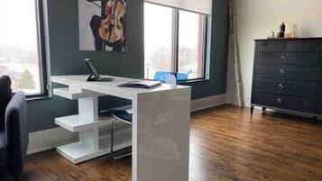 A modern office space with a white desk, a chair, and a large window.