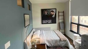A bedroom with a bed, a window, a ladder, and a poster on the wall. - The Quarters | Suite 5 (Grafton)