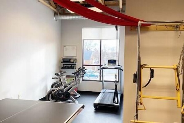 A gym with exercise equipment, a treadmill, and a red curtain.