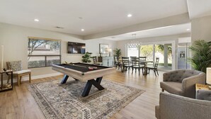 Een ruime woonkamer met een pooltafel, een eethoek en een comfortabele zithoek.