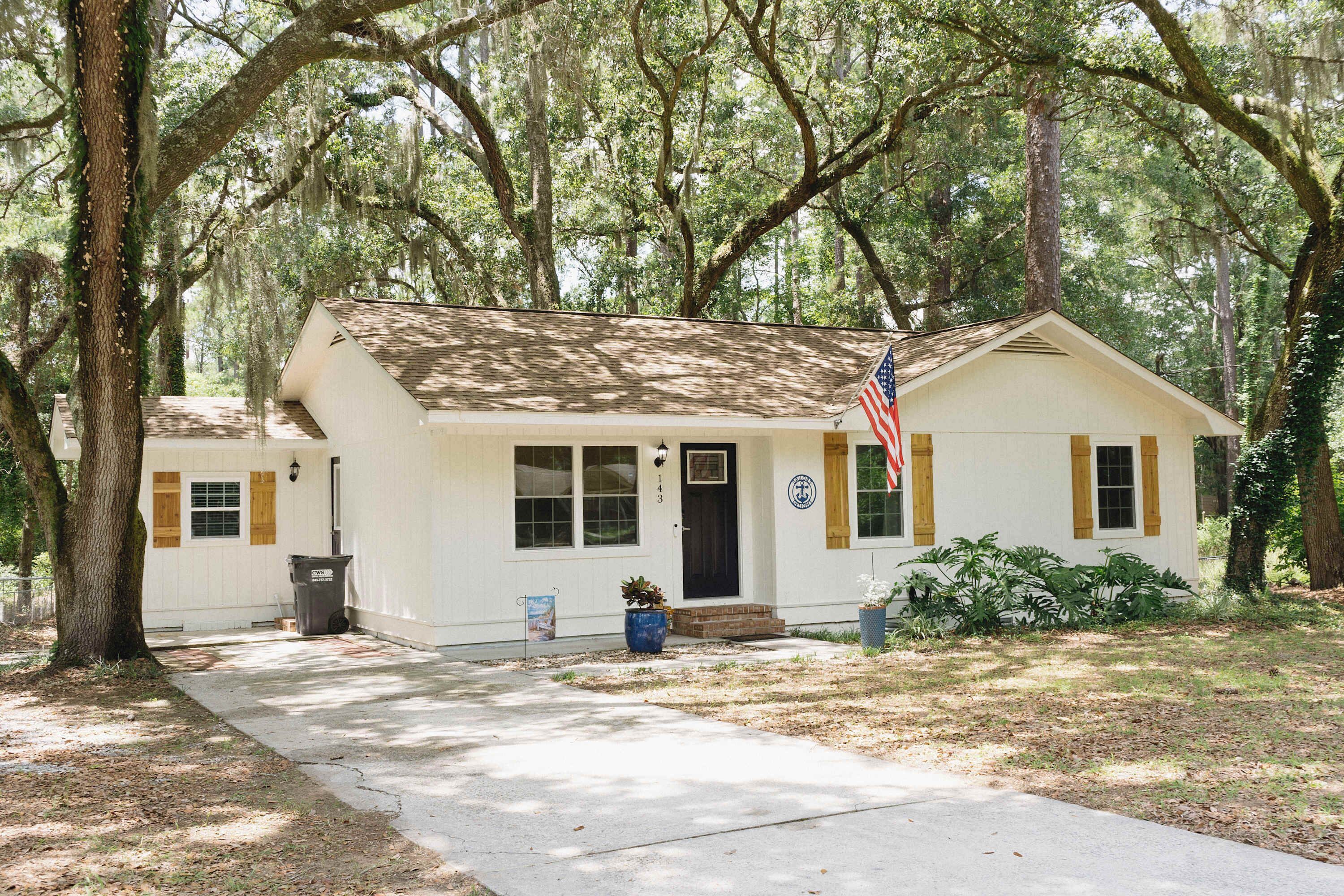 A small white building with a dark roof, an American flag, and a mailbox.