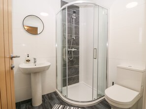 A modern bathroom with a glass-enclosed shower, a pedestal sink, and a toilet. - White Bull House (Amlwch)