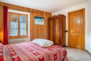 Een slaapkamer met een bed, een houten garderobe en een raam met gordijnen.