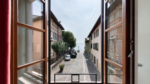 Blick durch ein Fenster auf eine Straße mit Gebäuden, parkenden Autos und blauem Himmel.