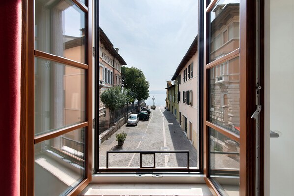A view through a window of a street with buildings, parked cars, and a clear sky.
