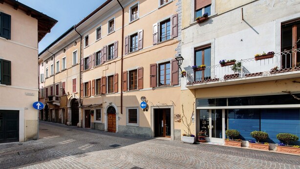 Une rue pavée bordée de bâtiments à l’architecture traditionnelle, un ciel dégagé et des panneaux de signalisation.