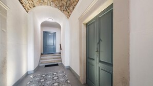 Un couloir avec un sol à motifs, une porte verte et un escalier menant à une autre pièce.