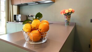 Un plan de travail de cuisine avec un saladier en verre rempli d’oranges et un vase de fleurs.