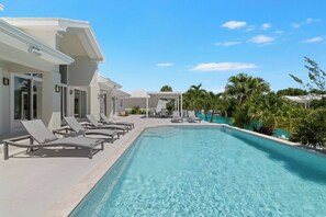 A modern resort with a clear swimming pool, sun loungers, and a covered patio area.