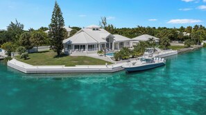 A waterfront property with a pool, a boat dock, and a large tree.