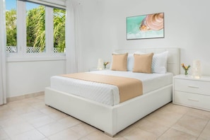 A bedroom with a bed, a nightstand, a window with curtains, and a wall-mounted picture.