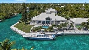 A large waterfront property with a pool, multiple buildings, and a dock with a boat.