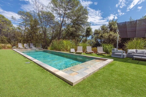 A rectangular swimming pool with a tiled edge, surrounded by a well-maintained lawn and several lounge chairs. - Apartment 'Grand Appartement Valeriane' with Mountain View, Shared Pool and Wi-Fi (Trans-en-Provence)