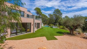 Ett modernt hus med en swimmingpool, en välskött gräsmatta och en grusuppfart.