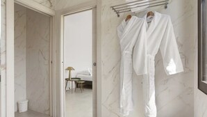 A hotel room with a marble floor, a bed with white linens, a bedside table with a lamp, and a towel rack with two white robes. - Holiday Home 'Rez De Villa Pour 8 Valeriane' with Shared Pool, Private Garden and Wi-Fi (Trans-en-Provence)