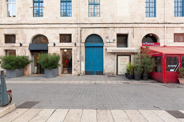 A building with a blue door, potted plants, and a red awning.