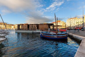 A canal with boats, a wooden building, and a cityscape with buildings in the background.