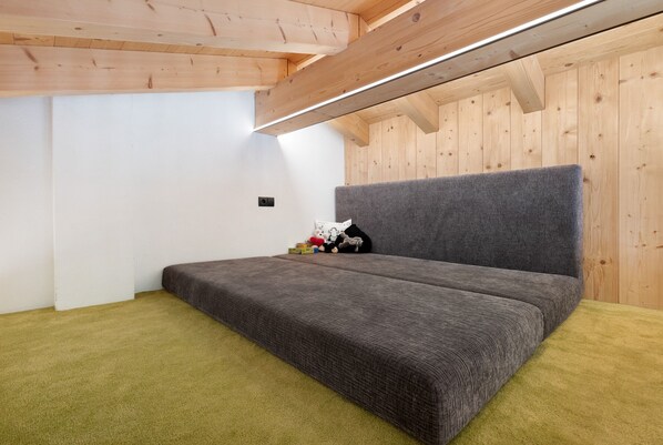 A room with a bed, wooden ceiling beams, and a white wall. - Chalet 'Berg' with Mountain View, Private Terrace and Wi-Fi (Selva dei Molini BZ)