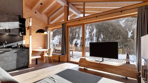 En modern inredning med kök, matplats och stora fönster som ger utsikt över en snötäckt skog.