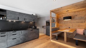 A modern kitchen with grey cabinets, a wooden dining area with a bench, and a pendant light.