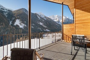 Une terrasse en bois offrant une vue sur des montagnes enneigées.
