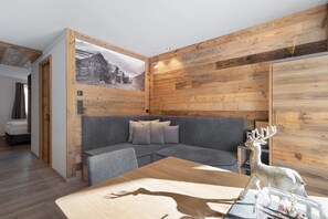 Een modern interieur met een houten wandpaneel, een grijze bank en een tafel met een beeldhouwwerk van een hert.