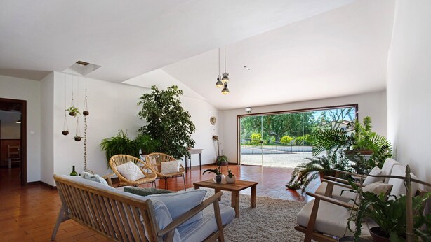 Uma sala de estar ampla, com teto alto, móveis de madeira e janelas grandes que oferecem vista para o exterior.