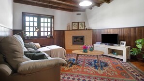 Uma sala de estar acolhedora com um sofá, lareira, televisão e tapete estampado.