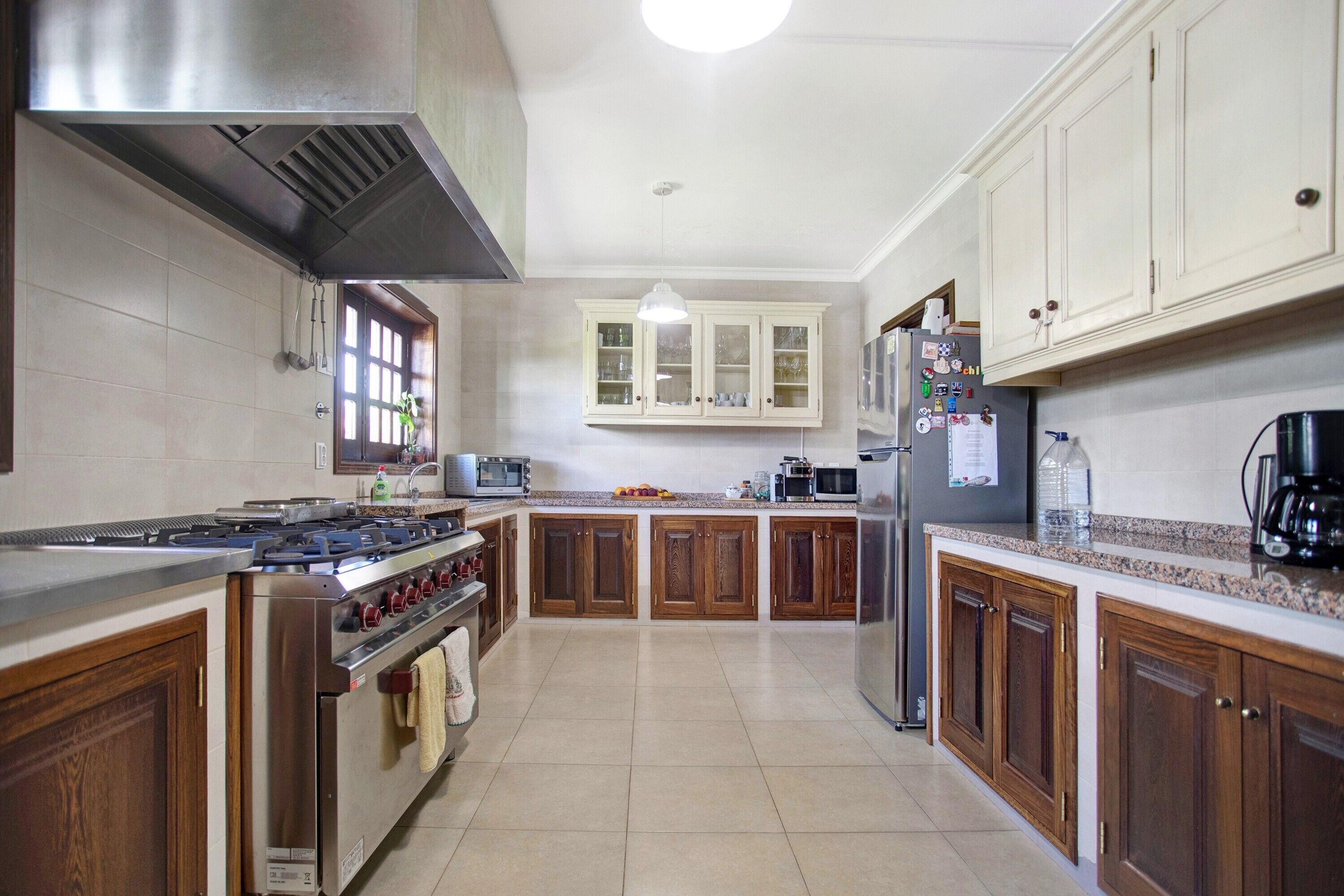 A kitchen with wooden cabinets, stainless steel appliances, and a tiled floor.