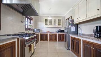 A kitchen with wooden cabinets, stainless steel appliances, and a tiled floor.