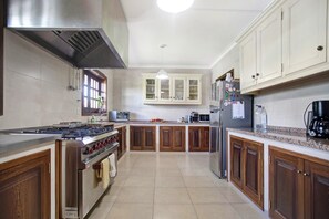 Una cucina con mobili in legno, elettrodomestici in acciaio inossidabile e pavimento piastrellato.