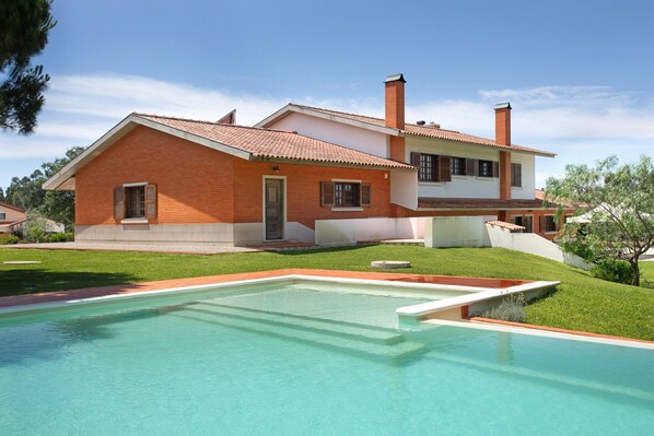 A two-story house with a swimming pool in front.