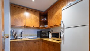 A kitchen with wooden cabinets, a microwave, a refrigerator, and a countertop with a kettle and a coffee maker. - Homity Dúplex Sierra Nevada Mt-3-p1-345 (Sierra Nevada)