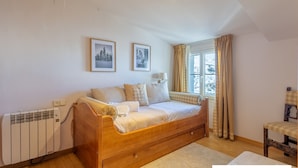 A cozy bedroom with a wooden bed, a radiator, a window with curtains, and two framed pictures on the wall. - Homity Dúplex Sierra Nevada Mt-3-p1-345 (Sierra Nevada)