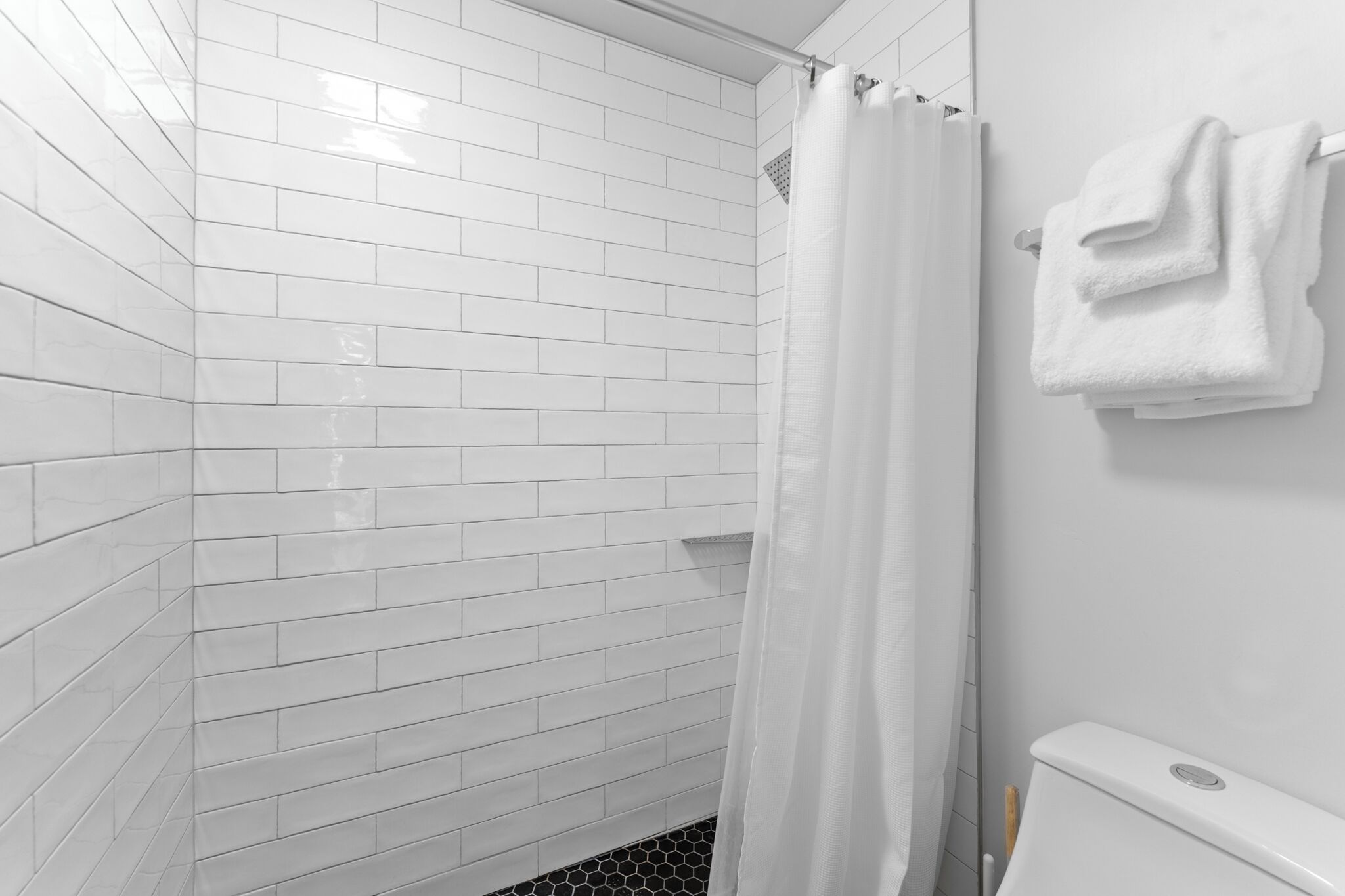 Un baño con paredes de azulejos blancos y una zona de ducha.