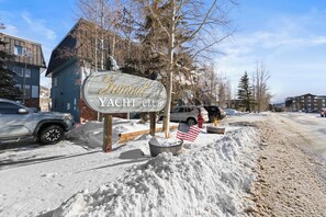Señal del Club de Yates Sunnyside, con el suelo cubierto de nieve y automóviles estacionados.