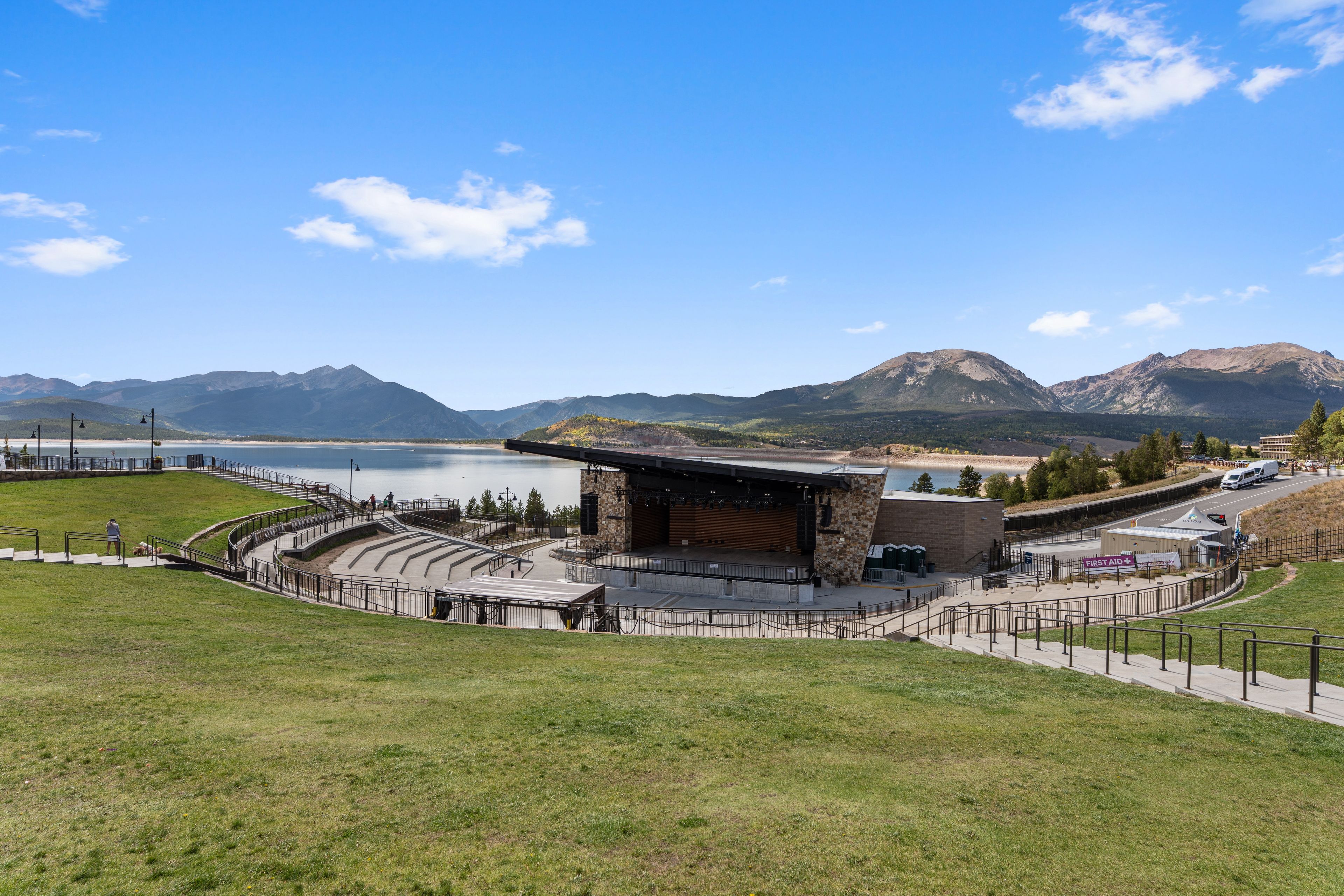 Un amphithéâtre en plein air doté de gradins, d’une scène et d’un décor pittoresque composé de montagnes et d’un lac.