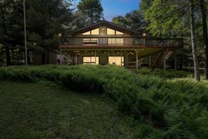 A two-story house with a balcony, surrounded by dense greenery. - Cozy Family Cabin • Steps to Lake • Canoe • Firepit • Pet Friendly (Pocono Lake)