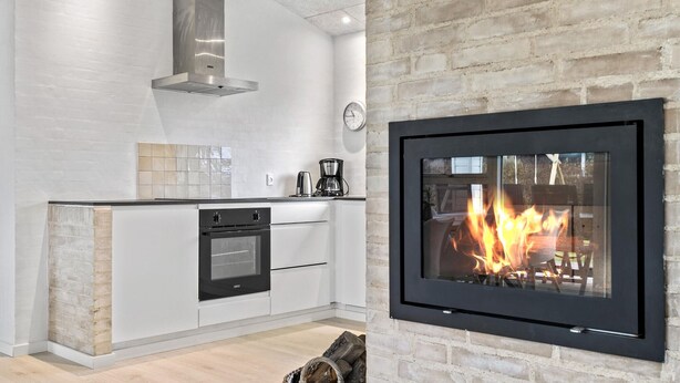 A modern kitchen with a built-in stove, a brick accent wall, and a fireplace. - Cozy home in Haderslev with WiFi (Haderslev)