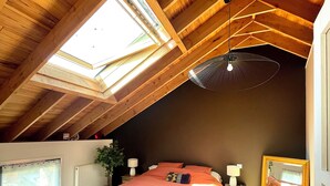 A bedroom with a sloped ceiling, a bed, bedside tables, a mirror, and a skylight. - Maison Plein Centre, Idéale Pour un Couple (Pont-l'Abbé)