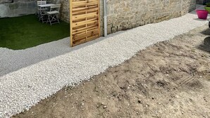 A stone building with a wooden door, a gravel path, and a small table with chairs. - Maison Plein Centre, Idéale Pour un Couple (Pont-l'Abbé)