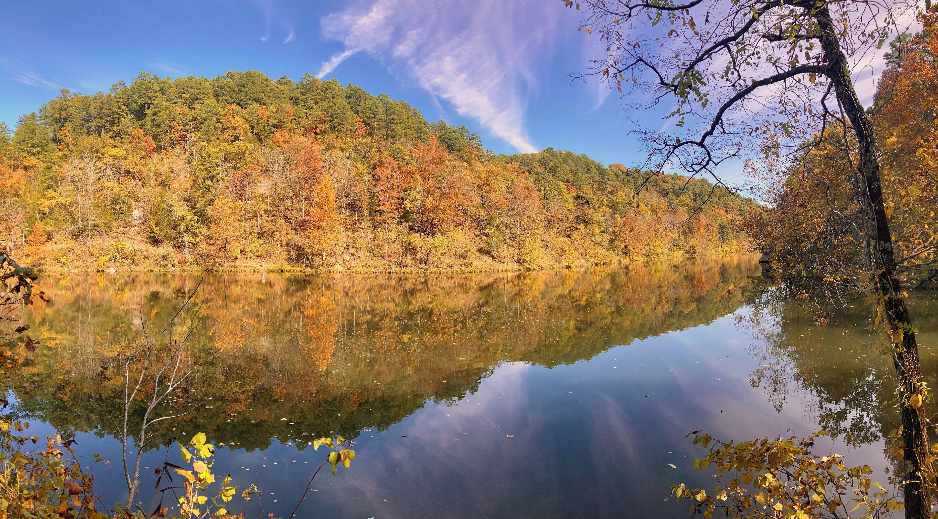 Un lac paisible qui reflète une forêt aux couleurs automnales.
