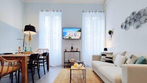 A modern living room with a dining area, a sofa, a TV, and a coffee table.