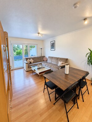 A modern living room with a sofa, a glass coffee table, and a dining table with chairs. - TOP Appartment Nähe Schalke Stadium, Veltins Arena ist 10 min zu Fuß Entfernt (Gelsenkirchen)