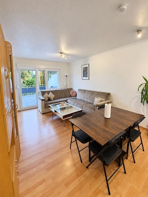 A spacious living area with a wooden dining table, a sofa, and a coffee table. - TOP Appartment Nähe Schalke Stadium, Veltins Arena ist 10 min zu Fuß Entfernt (Gelsenkirchen)