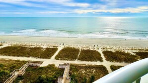 Una playa con un camino de madera y un paseo marítimo que conduce a una estructura.