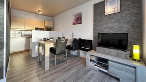 Un salon moderne comprenant un coin repas, une cuisine et un téléviseur.